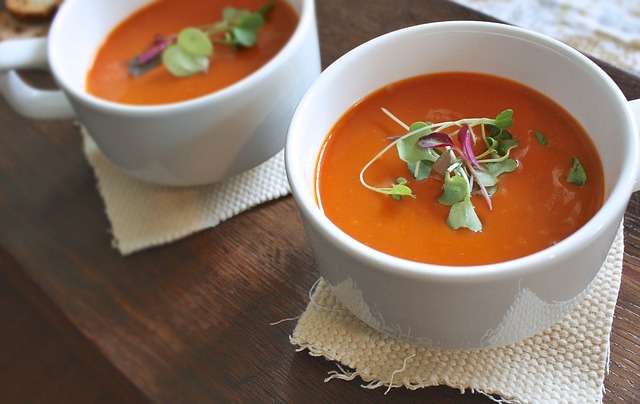 Image of 2 bowls of tomato soup garnished with salad leaves